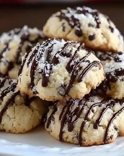 Nonna said ricotta makes cookies “whisper-soft,” the kind you bite and suddenly remember every good thing. I can still see her tapping the sieve so powdered sugar fell like tiny snowflakes over our kitchen table. Her measuring spoons were mismatched and a little bent, which meant every batch tasted a touch different—and somehow that felt like luck. We’d wait for the chocolate drizzle to set and pretend we had patience. The Dreamiest Holy Cannoli Cookies Recipe 🍪 Holy Cannoli Cookies Recipe 🍪 I