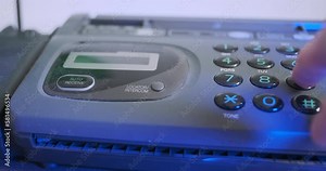 Man's hand dials 911 rescue service on an old push-button telephone. Front view, close-up. Red blue light flashing on the background