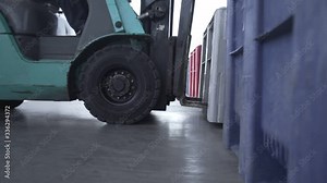 Loaders lift big pastic box in warehouse logistics center