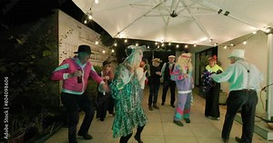 Capture the vibrant and energetic atmosphere of a retro-themed dance party with guests donned in colorful and flamboyant costumes. This footage showcases a group of partygoers dancing and enjoying