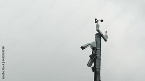 High pole with spinning anemometer or weather wind vane propeller and another measure gauges for meteorology conditions and forecasts.
