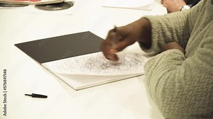 African woman close up hand drawing random circle patterns on paper practicing learning patterns in arts school wearing cosy warm jumper moving hand without stopping Stock Video