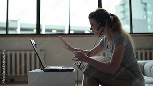 An angry and annoyed woman throws a frozen laptop off the table. Slow technique irritates an unbalanced person