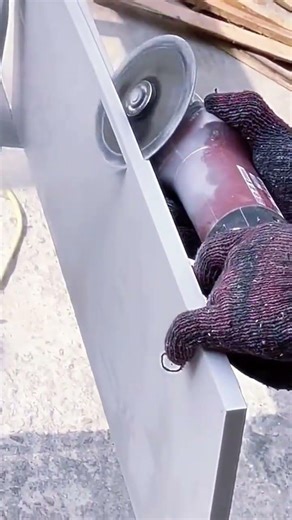cutting ceramic tiles precisely with handheld electric power grinder while wearing protective gloves