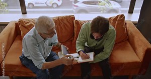 After class, a student and their professor collaborate in the library, both deeply focused as they work together on academic material.