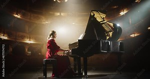 Talented Female Pianist Captivates the Audience with Her Masterful Performance on a Grand Piano. On a Theater Stage, Her Fingers Move Across the Keys, Creating Beautiful Classical Music