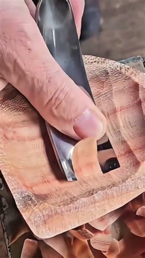 shaping a wooden bowl using a curved carving tool to create a smooth surface with intricate textures