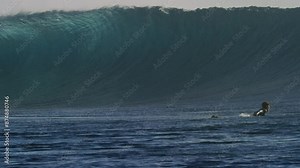 Surfer paddles to get out of impact zone as wave at Cloudbreak Fiji comes crashing down sparkling with mist