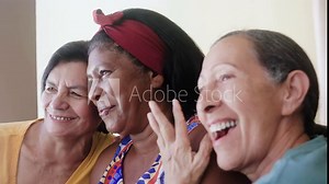 Happy multiracial senior women having fun together at home. Older generation people hug each other