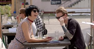 Couple using his phone during the date. Checking messages, browsing the internet, or using it as a conversation starter or to share something interesting with girl. People lifestyle.