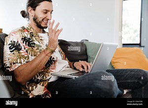 Young happy man sitting on couch at home looking at laptop studying online using computer, friendly guy watching webinar video Stock Photo - Alamy