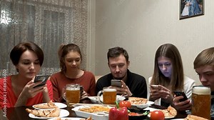 Friends at the party instead of having fun, use their smartphones, chatting and browsing the social networks. Group of friends use their phone at the same time. Group of friends on the couch talking