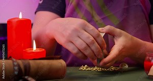 Fortune teller hand holds tarot deck in her hand, lays it out on table with candles, ancient scroll Layout of metaphorical card, predicting future, subconscious clues Witch in bright scarf prediction