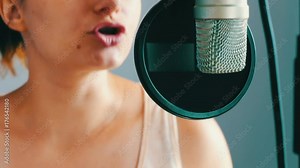 Young girl sings something in a studio microphone at a recording studio