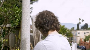 Man homeowner repairing a fence outside a neighborhood in Southern California