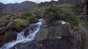 A man walking beside a mountain waterfall