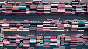 Trucks and cars driving between stacked cargo containers top down aerial view. Containers at logistics terminal. Cargo container outdoor warehouse
