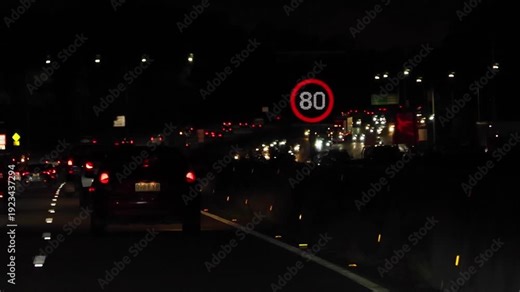 Nighttime Highway Traffic with Illuminated Eighty Speed Limit Sign