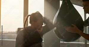 Fitness, boxing and personal trainer coaching a woman in mma training, exercise and workout in a gym studio. Sports, healthy and strong girl boxer learning fighting skills from a fighter or mentor