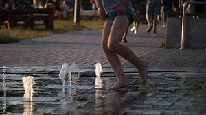 Kids playing in fountain with waterspouts coming from underneath, happy and curious