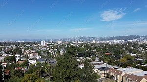 Aerial pan across LA neighborhood Larchmont. Beverly Street down below with easy morning traffic on the street. Blue sky with a few clouds.