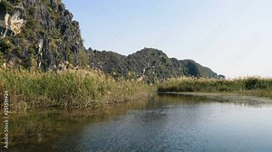 Panorama view of beautiful karst scenery, wetlands seen from the boat at Van Long Nature Reserve, Vietnam. Tourists traveling in small boat in tranquil landscape.