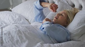 Menopausal mature woman suffering with insomnia awake in bed at home - shot in slow motion