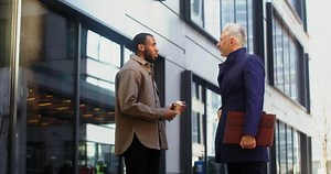 Two men talking outside a building