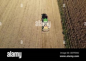 Aerial drone view of tractor planting crops with rear seeding machine on large farmland in southern countryside modern agricultural field operations