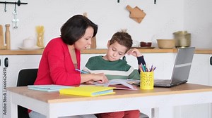 Female private tutor helping young student with homework at desk in bright child's room. mother helps son to do lessons. home schooling, home lessons.