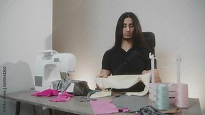 A man sews clothes while sitting at a table with a sewing machine