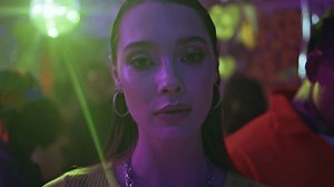 Trendy model posing nightclub dancefloor at weekend night closeup. Thoughtful beauty under neon club lights portraying pensive mood. Portrait of stylish confident woman looking camera under disco ball