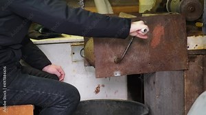 A man turns a homemade device for extracting cedar nuts from Siberian pine cones.