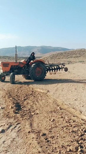 Operating an Orange Tractor in Rural Landscape