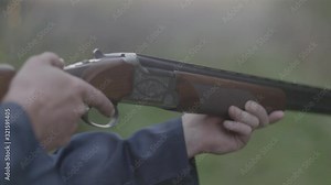 Close up of someone firing an over under double barrel shotgun, and then opening it to eject the empty shells