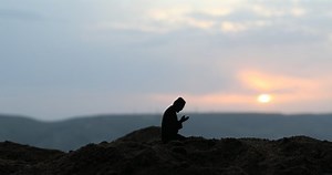 Silhouette of mosque building on sunset. Ramadan Kareem background. Realistic mosque miniature with prayer silhouette. Selective focus