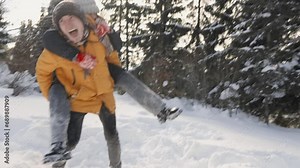 Loving couple enjoying romantic moments hugging and playing and having fun in snowy meadows near snow-covered trees on winter vacation