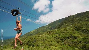 Young slim woman on zip line with gopro in hands, Puerto Galera, Philippines