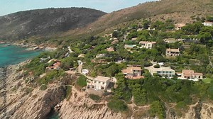 Mediterranean beach houses and turquoise water at Azure Coast, French Riviera Aerial view of the beautiful turquoise see-throughwater and sandy beach with rocky headlands and mediterranean style house
