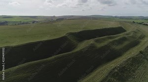 Aerial tracking along the northern side of the iron age hill fort known as Maiden Castle. Three levels of earthworks can be seen. Dorchester, Dorset.