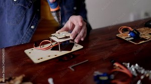 Robotic school project: Young student building robot vehicle at artificial intelligence programming class - STEM education concept - Focus on right hand holding wood piece
