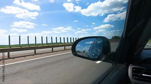 Picturesque view through the car window to empty road and natural landscape. Landscape in summertime. Cars drive along a high road with motion blur background. Car side mirror.