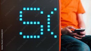 The word school moves on an electronic screen in a bus. Against the background, a child sits with a mobile phone in her hands in efetok bokeh. The concept of the designation of places.