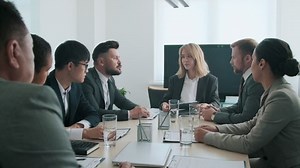 Representatives of two modern business groups signing agreement papers during meeting in board room