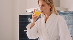Free stock video - Blonde woman drinking orange juice in the kitchen.