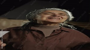 Vertical shot of mature gray-haired actress performing monologue emotionally on stage while having audition in theatre