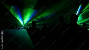 A modern laser light show, with a projection on smoke, a crowd of people watches the laser beams that turn into various lines and shapes. Outdoor performance.