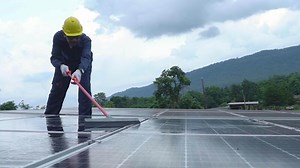 Download A Technician performing maintenance on solar energy Clean the solar panels with a brush at the solar power plant. for free