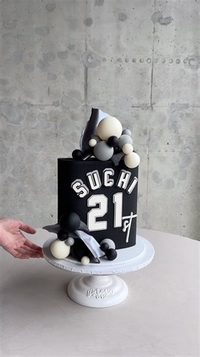 Squircle cake, kind of like a mix between a square and a circle, and it’s got this awesome black color and message that’s inspired by birthday boy’s favorite jerseys. To top it off with our chocolate balls and same silver chocolate waves, share your thoughts with us ☺️ | K CAKE