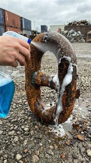 Hand spraying rust off chain